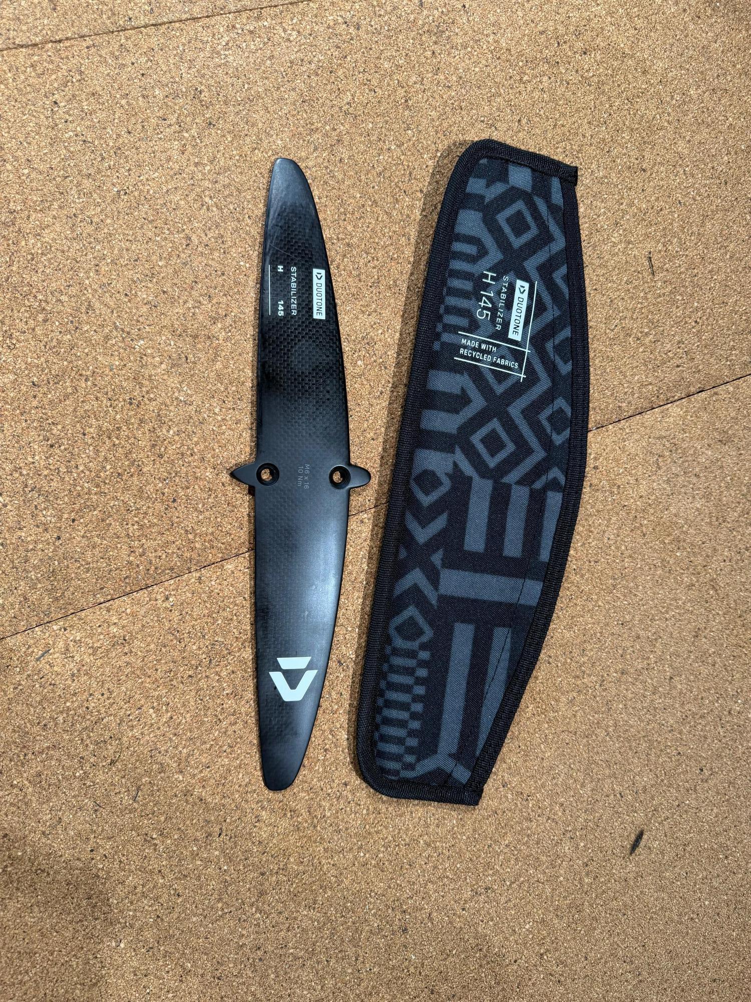 Used Duotone H 145 carbon foil stabiliser wing with branded protective cover on a cork surface.