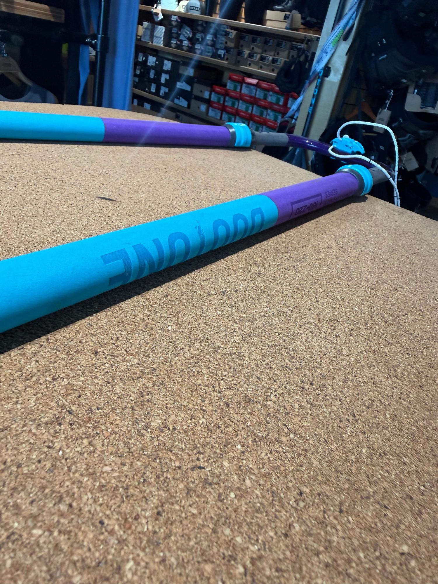 Used Duotone Platinum SLS 160-220 carbon windsurfing boom in blue and purple, resting on a cork surface.