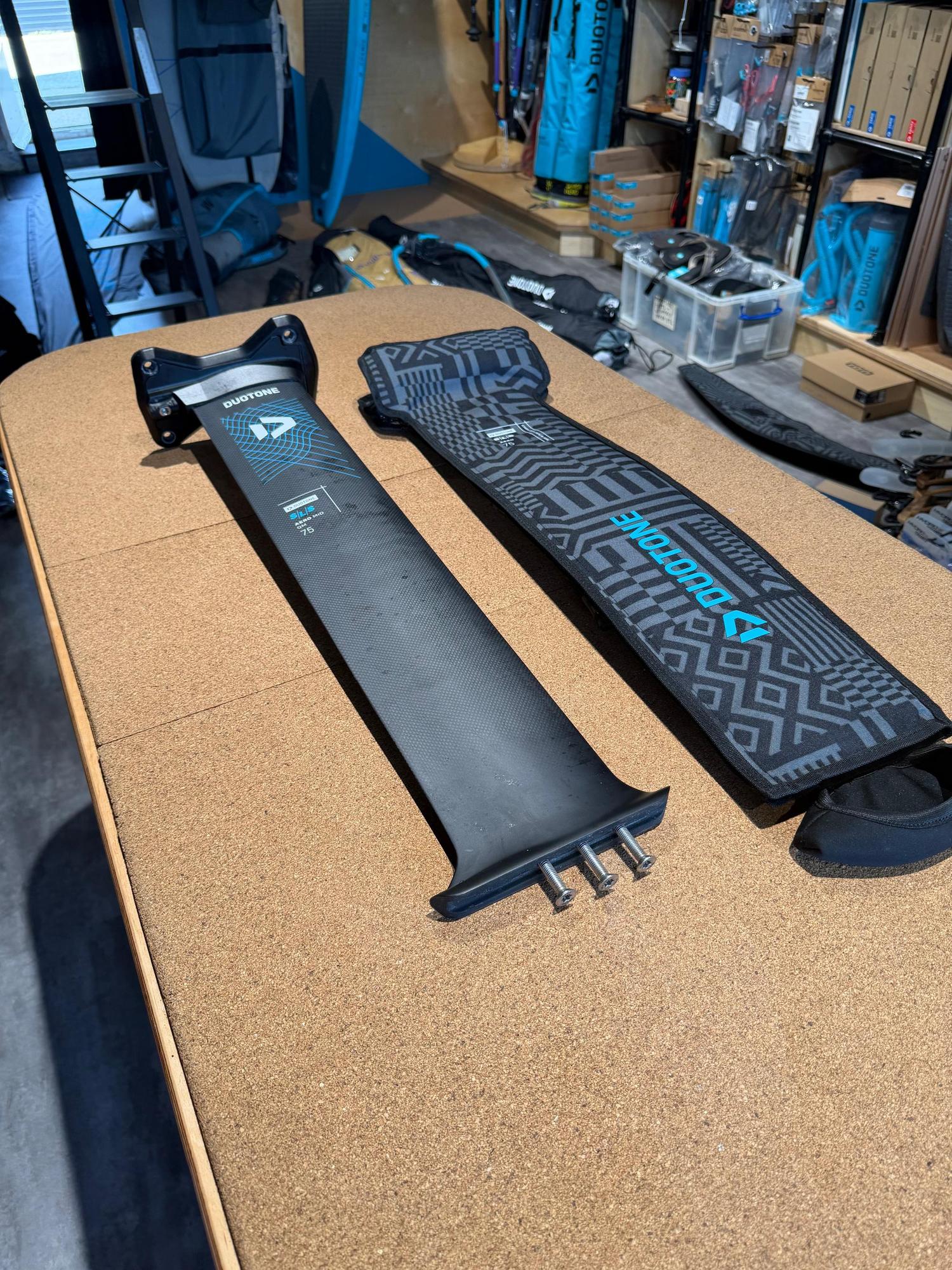 Used Duotone Aero Mid QM SLS 75cm carbon foil mast with Quick Mount system and protective cover on a workbench.