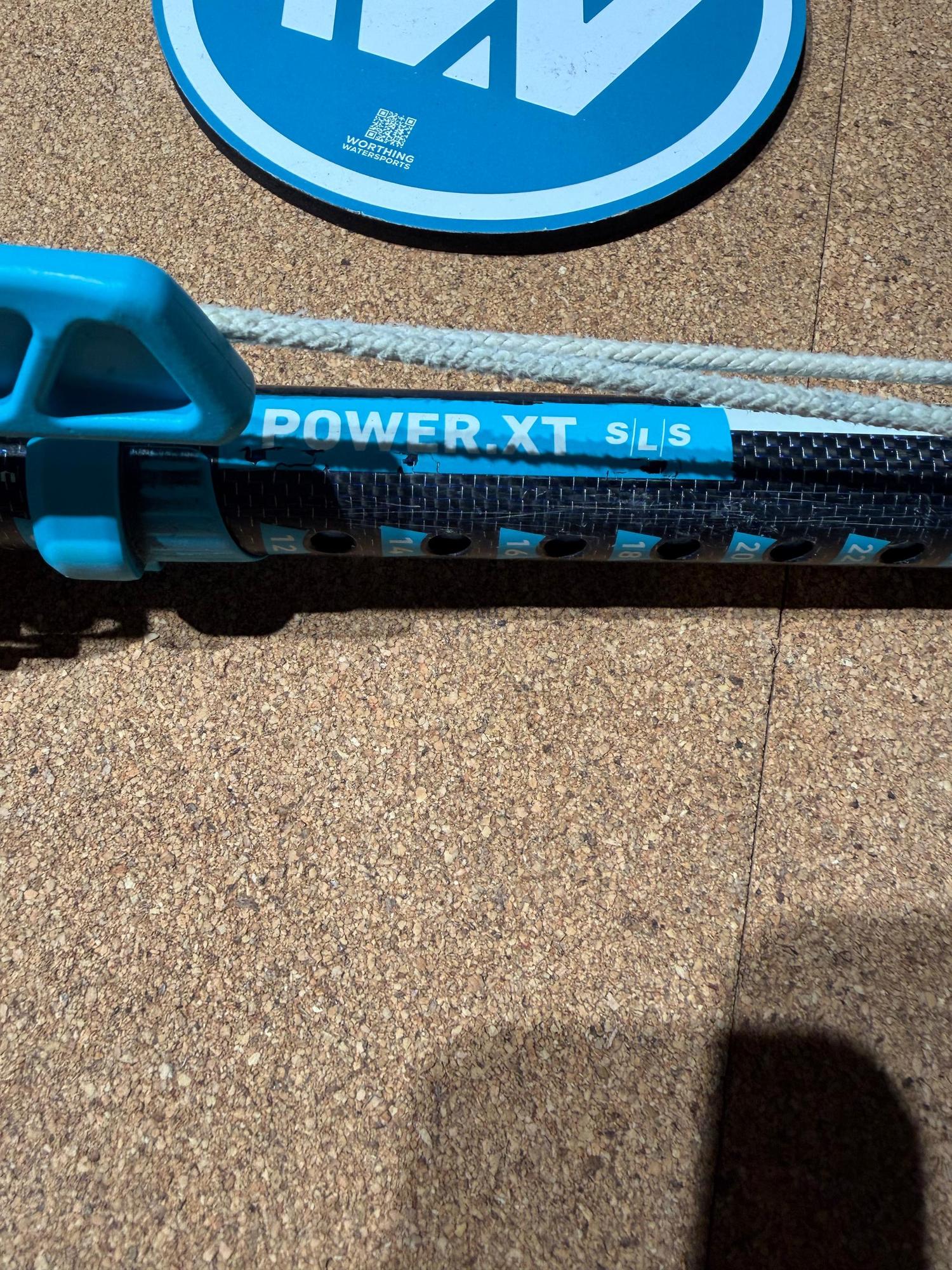 Duotone Power.XT 2.0 SLS carbon windsurfing extension with blue ratchet lever and adjustment markings on a cork surface.