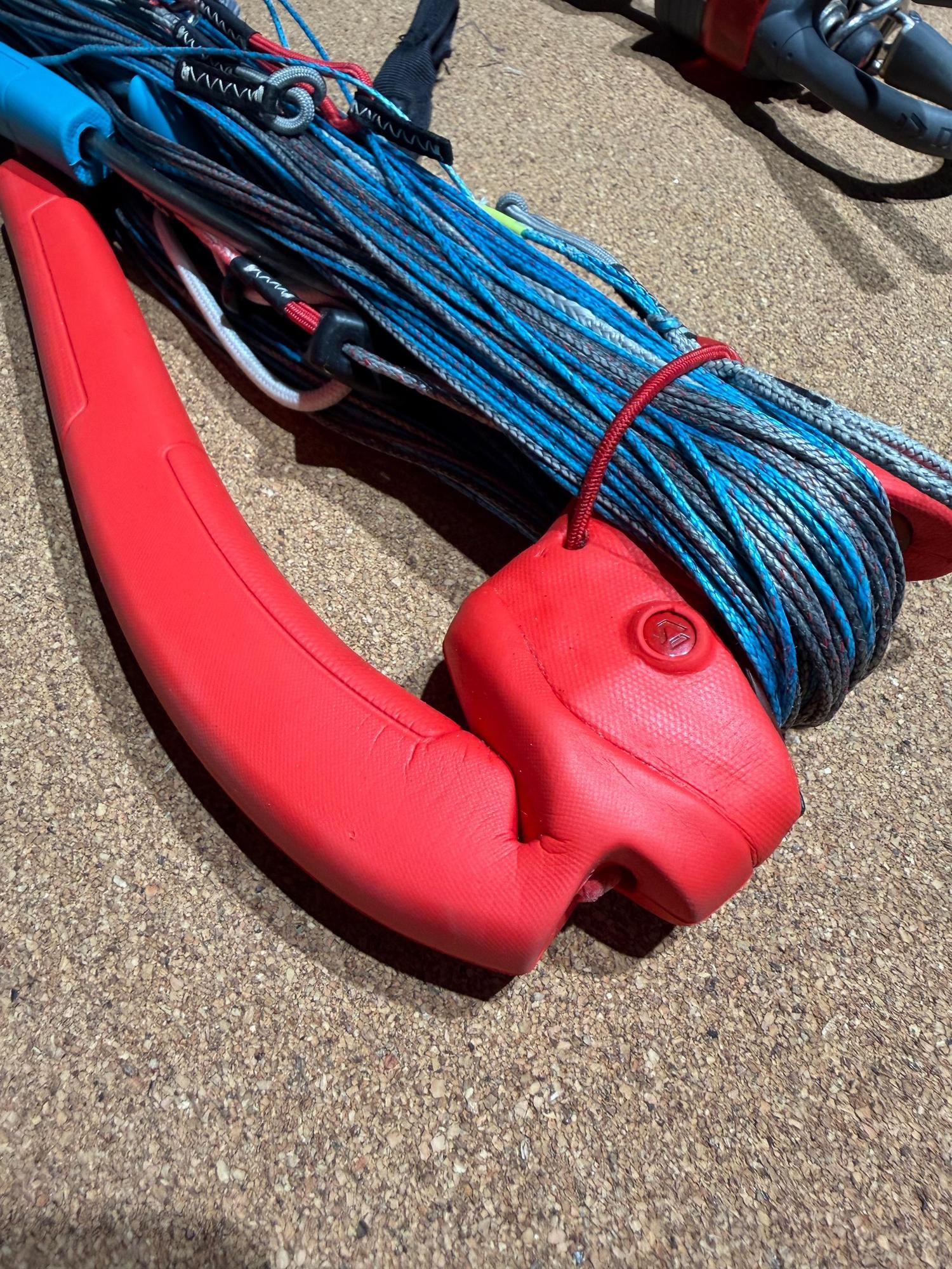 Used Duotone Trust Bar S-M with red grip, blue and grey kite lines, and Click-In safety system on a cork surface.
