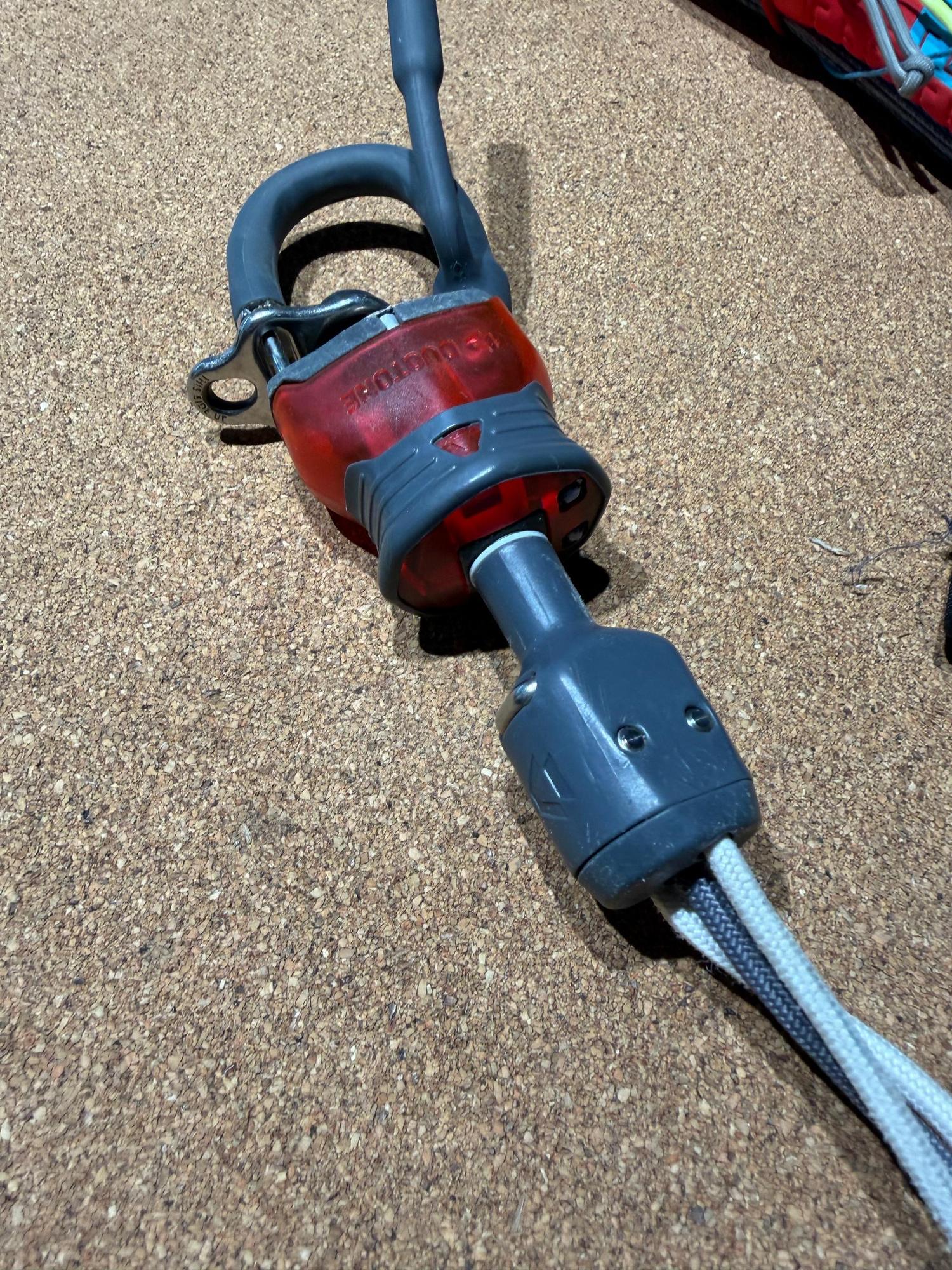 Used Duotone Trust Bar Click-In safety system with red release mechanism and grey lines on a cork surface.