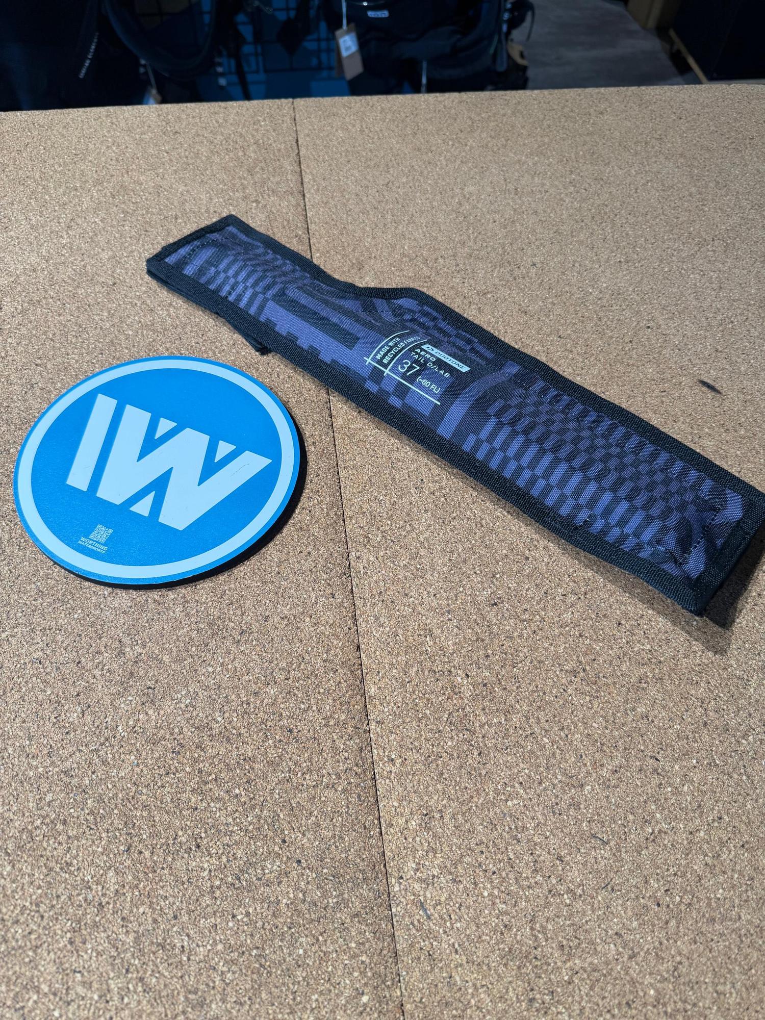 Duotone Aero Tail D/LAB 37cm fuselage component in a blue patterned protective sleeve on a cork surface.