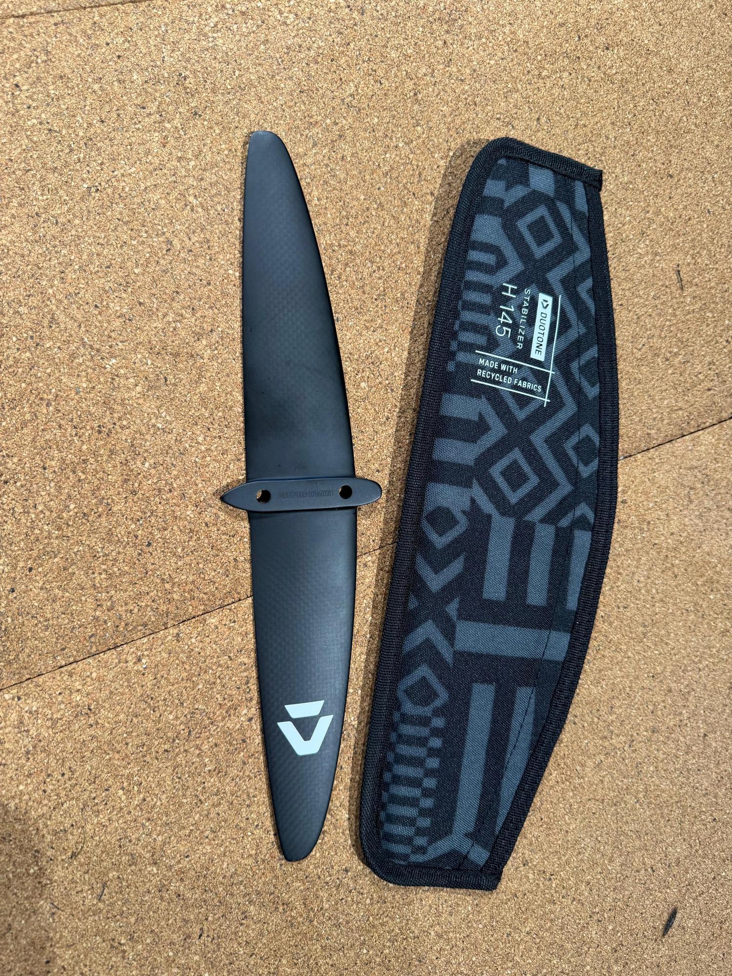 Used Duotone H 145 carbon back wing stabiliser with branded protective cover on a cork surface.