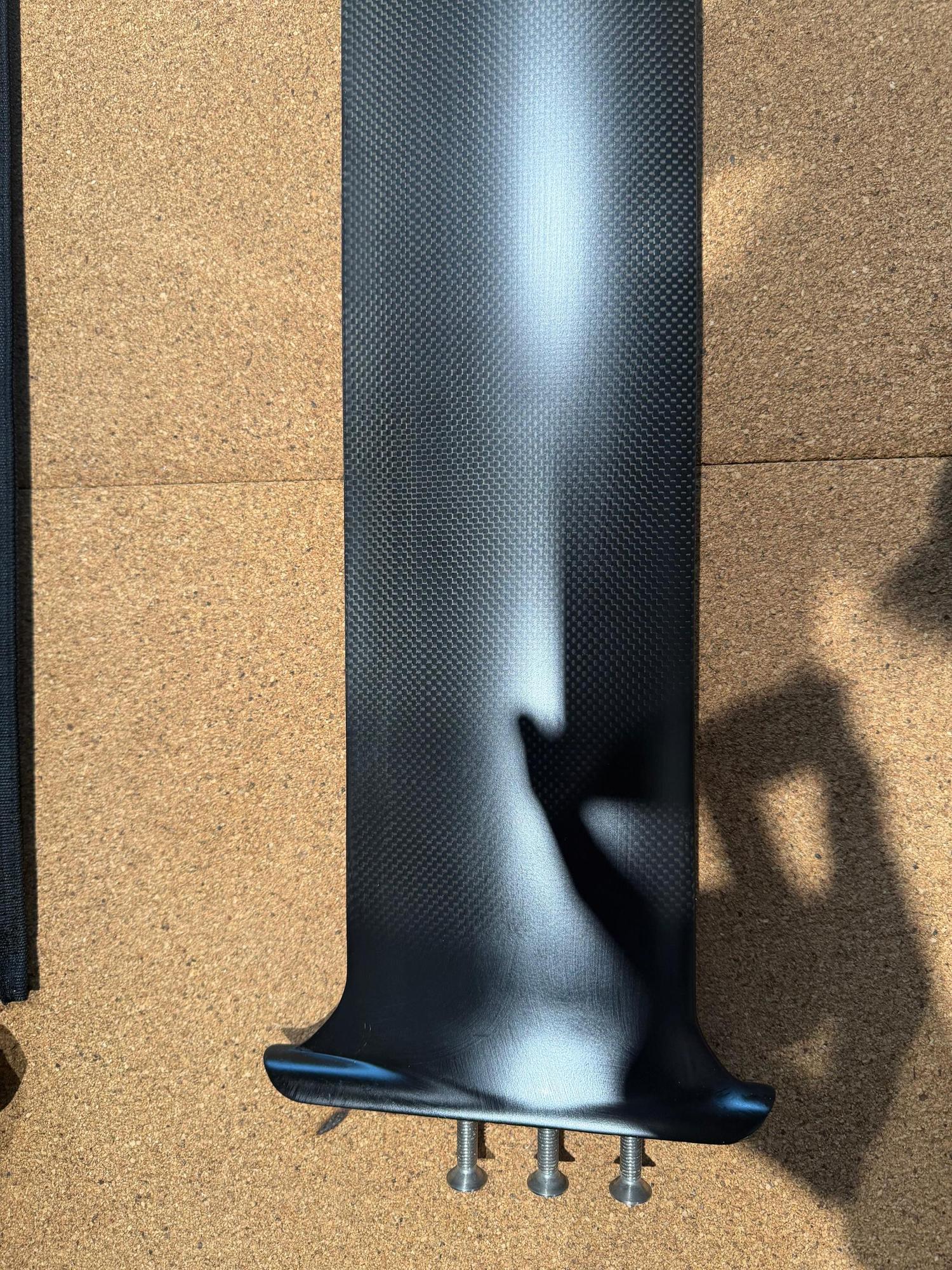 Used Duotone Aero Mid QM SLS 75 carbon foil mast with Quickmount base and track nut sleds on a cork surface.