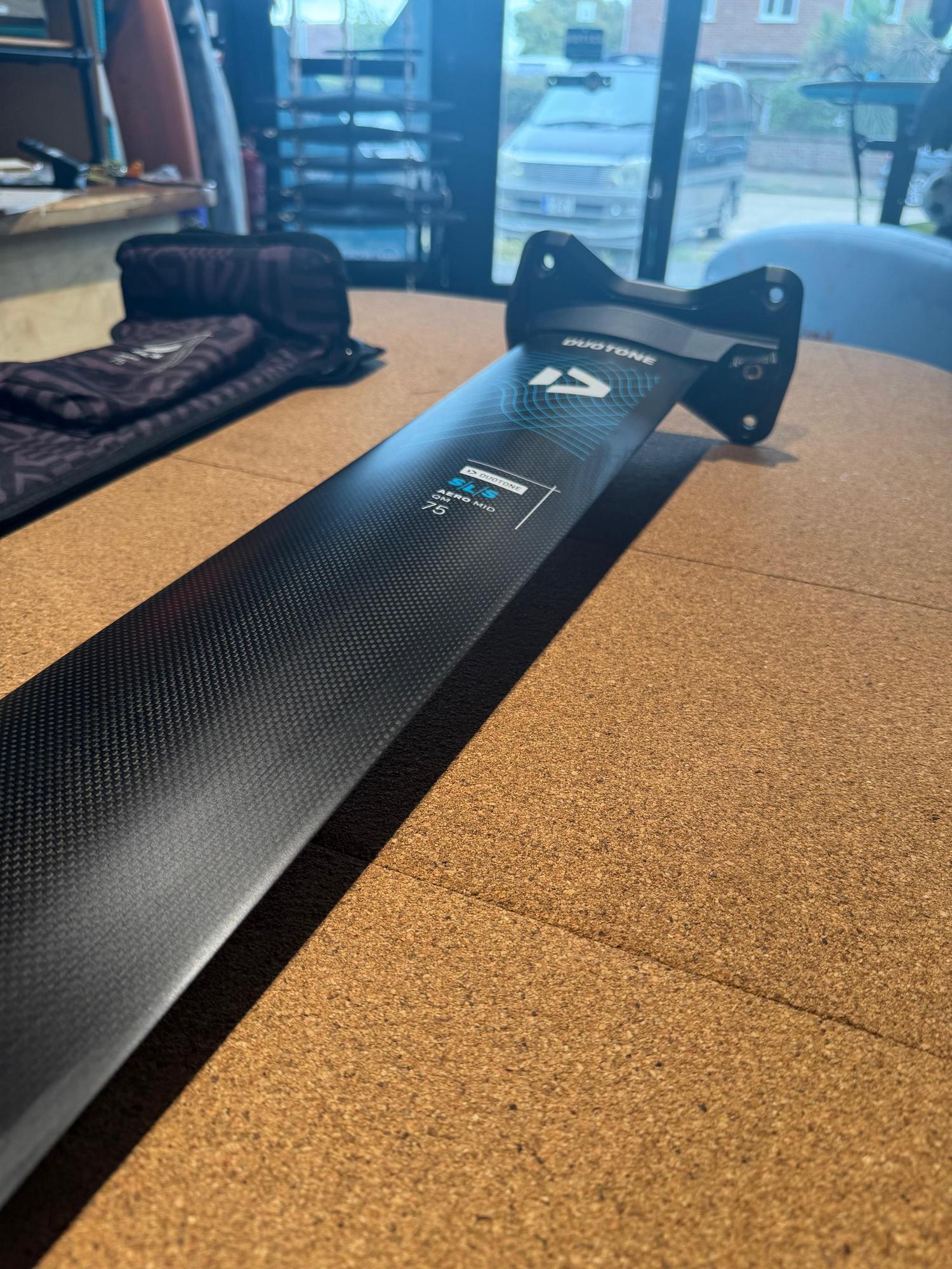 Black carbon Duotone Aero Mid QM SLS 75 mast with Quick Mount system, featuring blue branding on a textured surface.