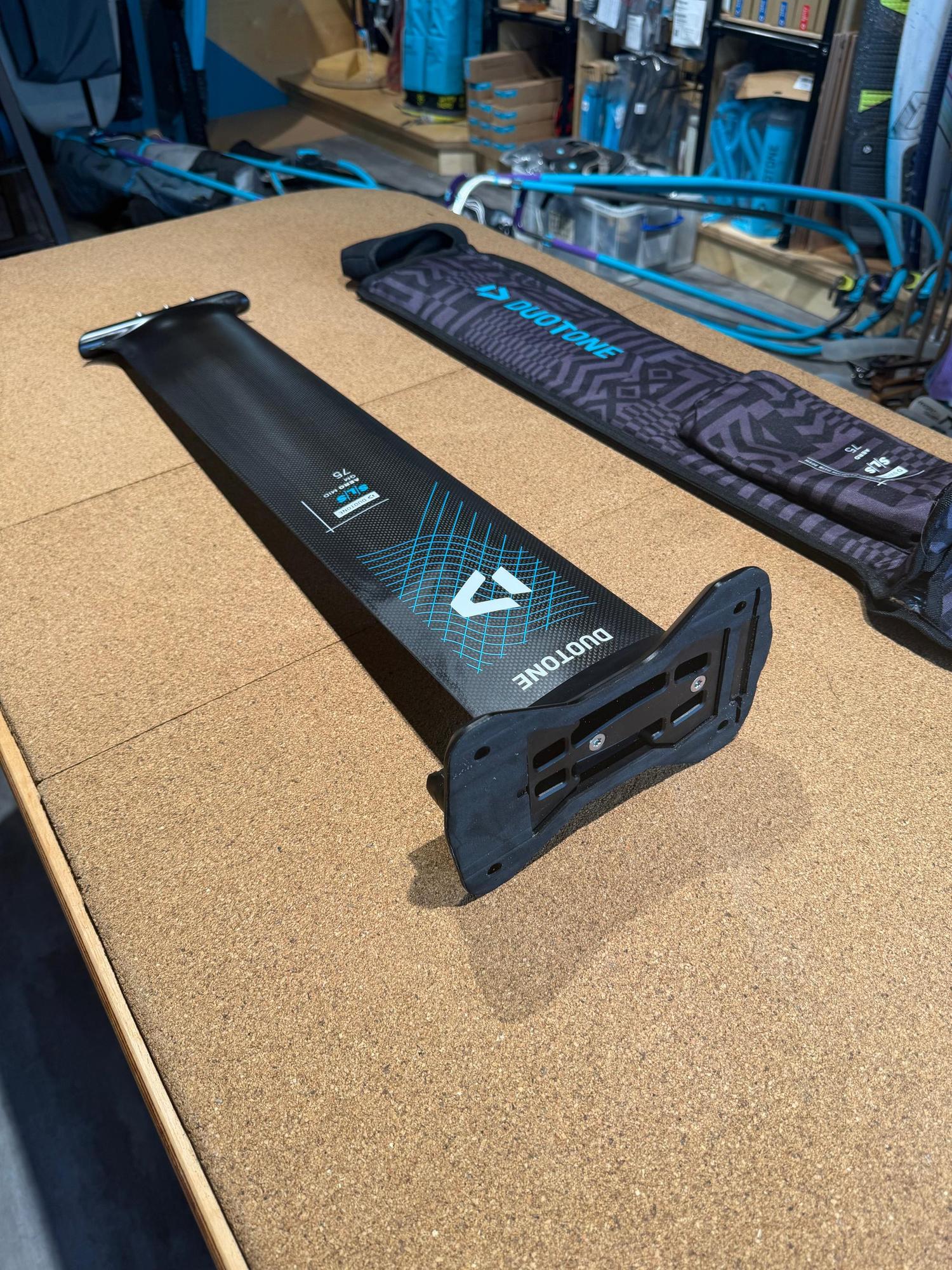 Used Duotone Aero Mid QM SLS 75 carbon foil mast with Quickmount system and protective cover on a cork surface.