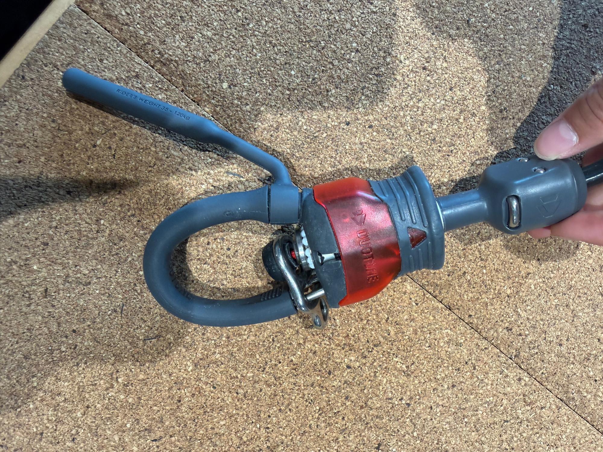 Used Duotone Click Bar 2026 S size with grey chicken loop and red safety release mechanism on a cork surface.