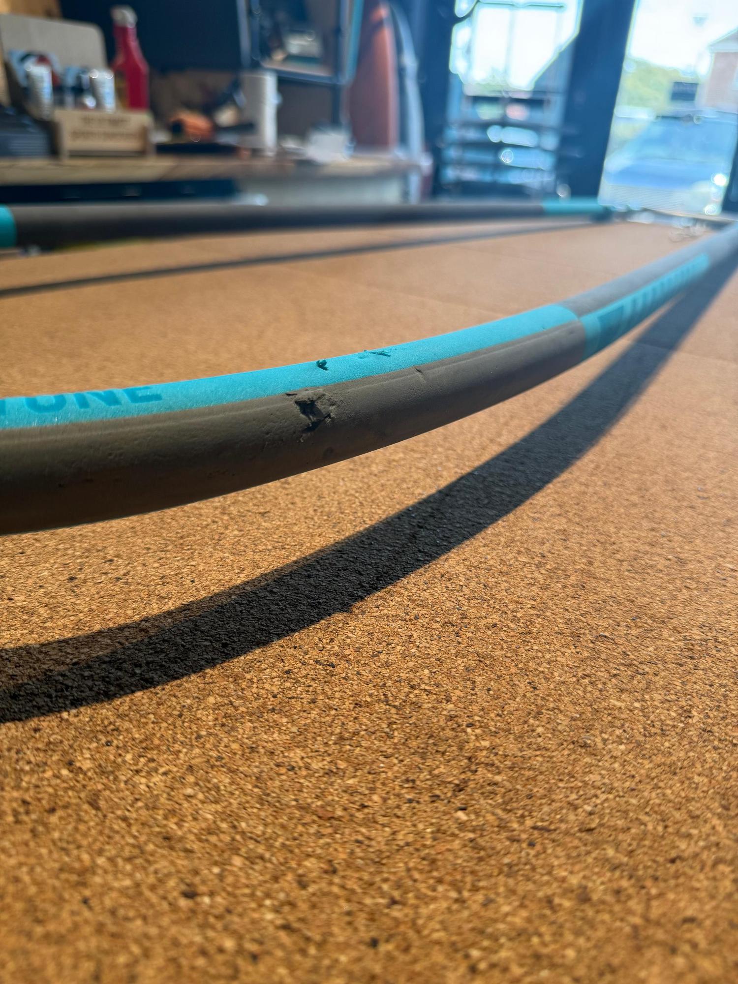 Used Duotone Silver Series Mega.Slim windsurfing boom in blue and black with visible grip scuffs on a cork surface.