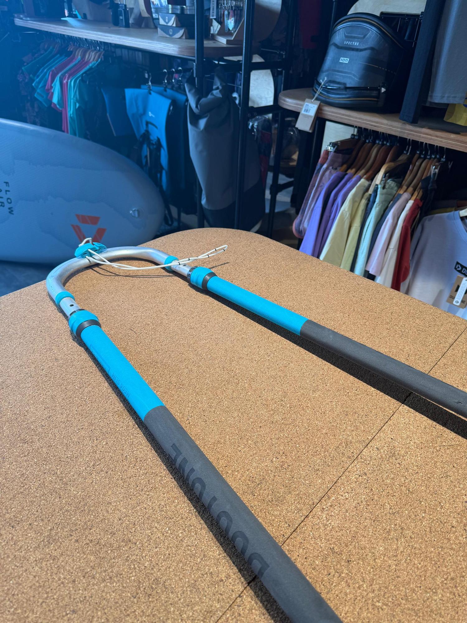 Duotone Silver Series Mega.Slim 140-200 windsurfing boom in silver and blue with black grip on a cork surface.