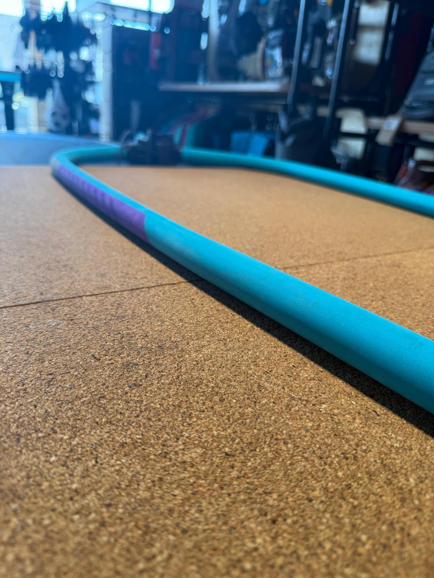 Used Duotone Platinum SLS carbon windsurfing boom in turquoise and purple on a cork surface.