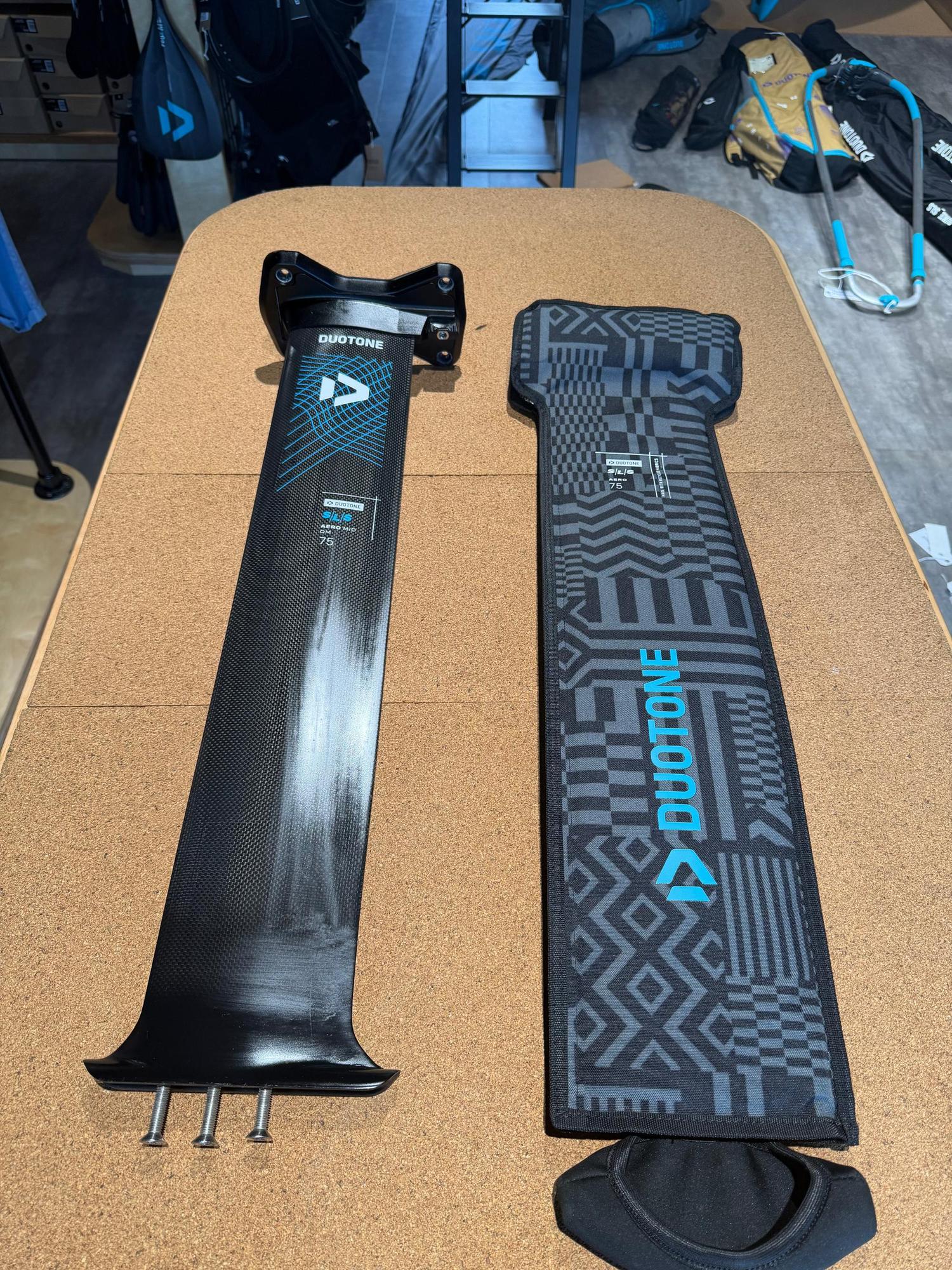 Used Duotone Aero Mid QM SLS 75 carbon foil mast with Quickmount system and protective cover on a cork table.