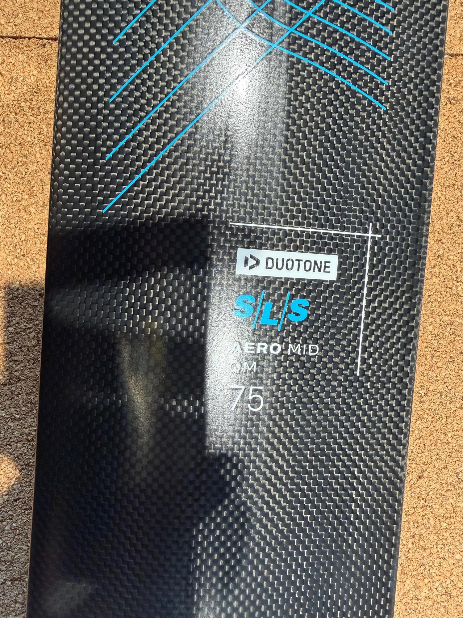Carbon fibre Duotone Aero Mid QM SLS 75 mast with blue graphic details and branding on a textured surface.