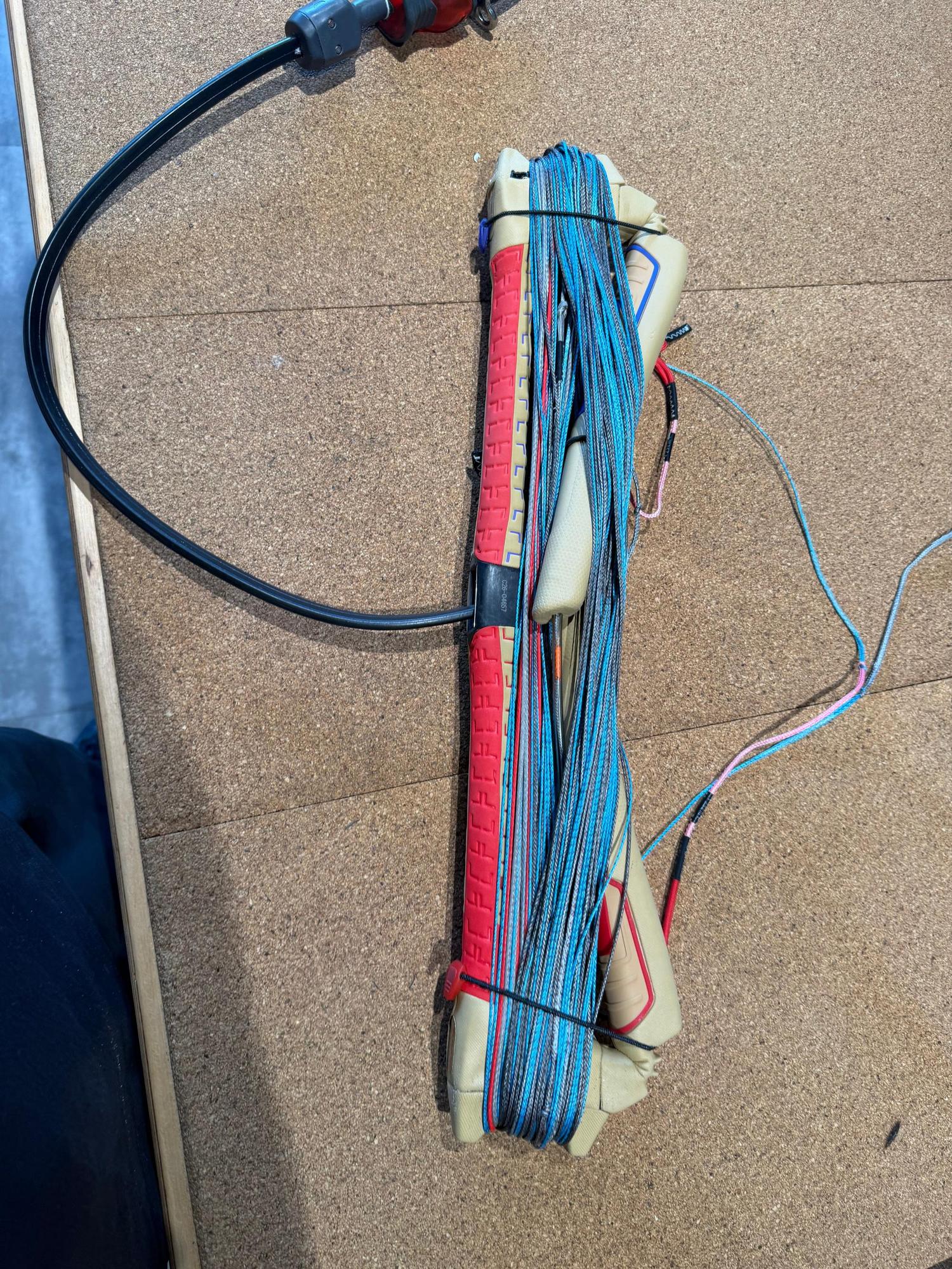 Used Duotone Click Bar Quad Control 2026 S size with red and beige grips, coiled lines, and black safety depower line.