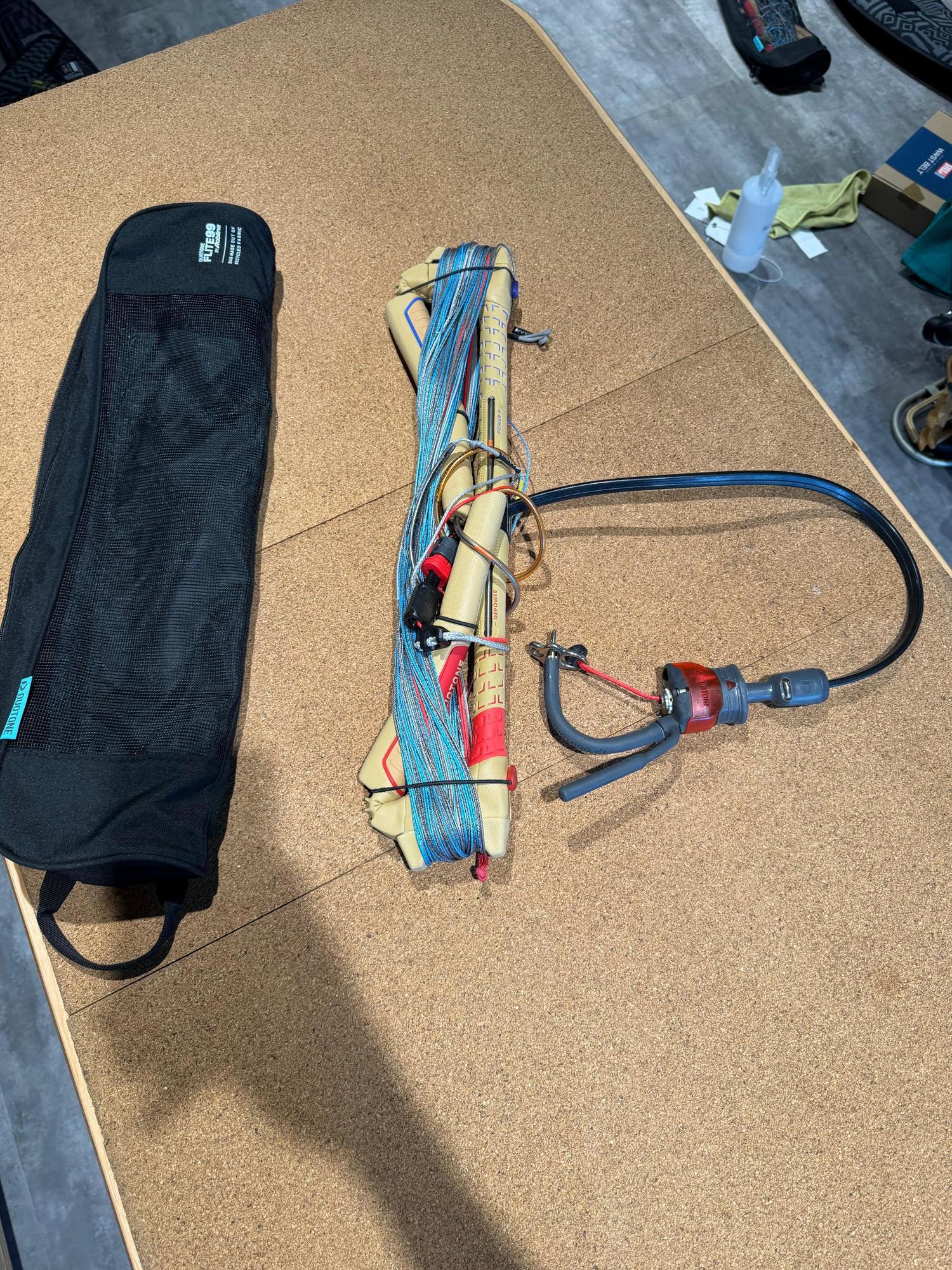 Used Duotone Click Bar Quad Control 2026 S/20-22 with blue lines and black storage bag on a cork surface.