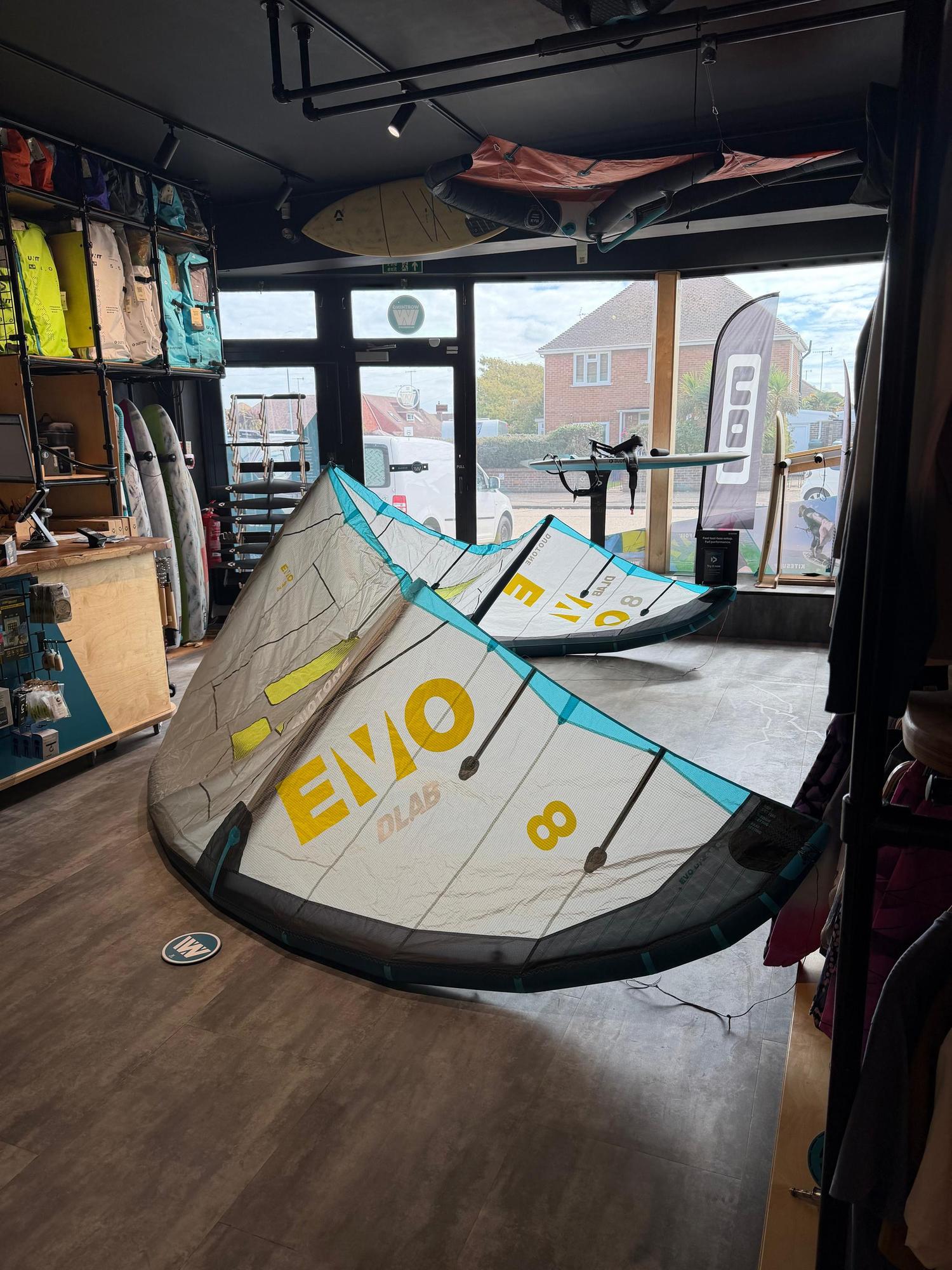Used 8m Duotone Evo DLAB kite in white, yellow, and blue Trinity TX fabric displayed on a shop floor.