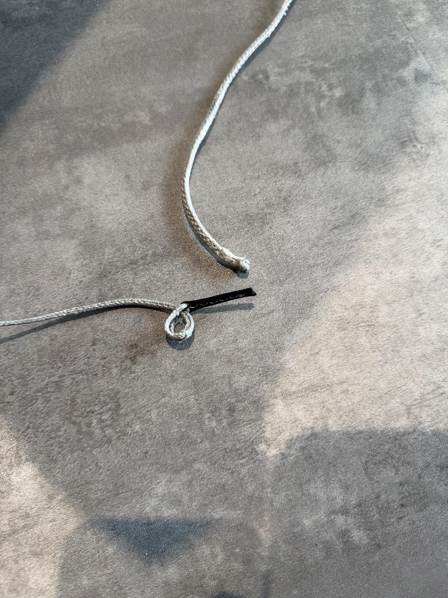 Close-up of a Duotone Evo DLAB kite pigtail showing minor fading on the grey cord and black connector.