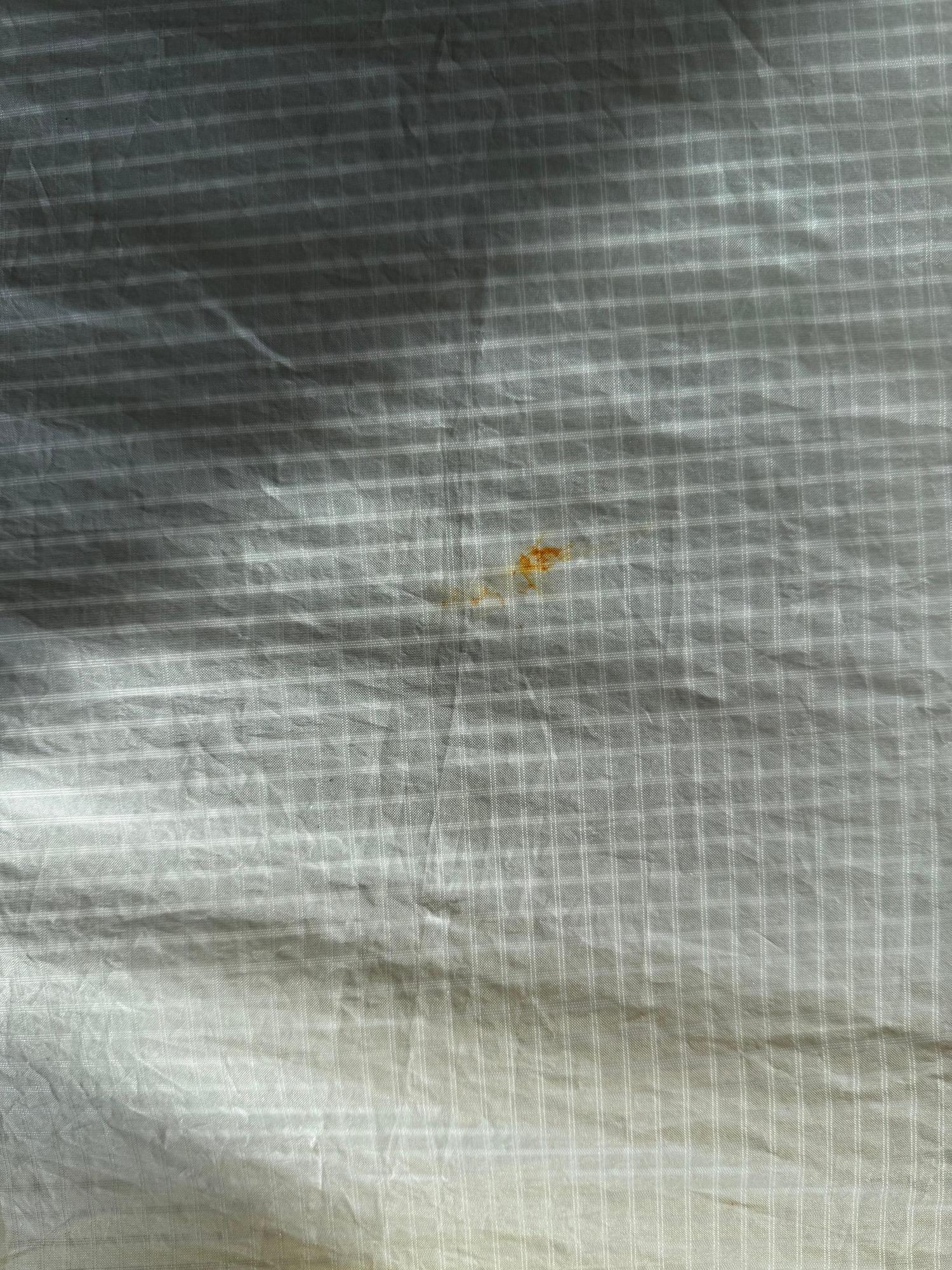 Close-up of white ripstop fabric on a Duotone Unit SLS wing showing a small orange stain on the grid pattern.