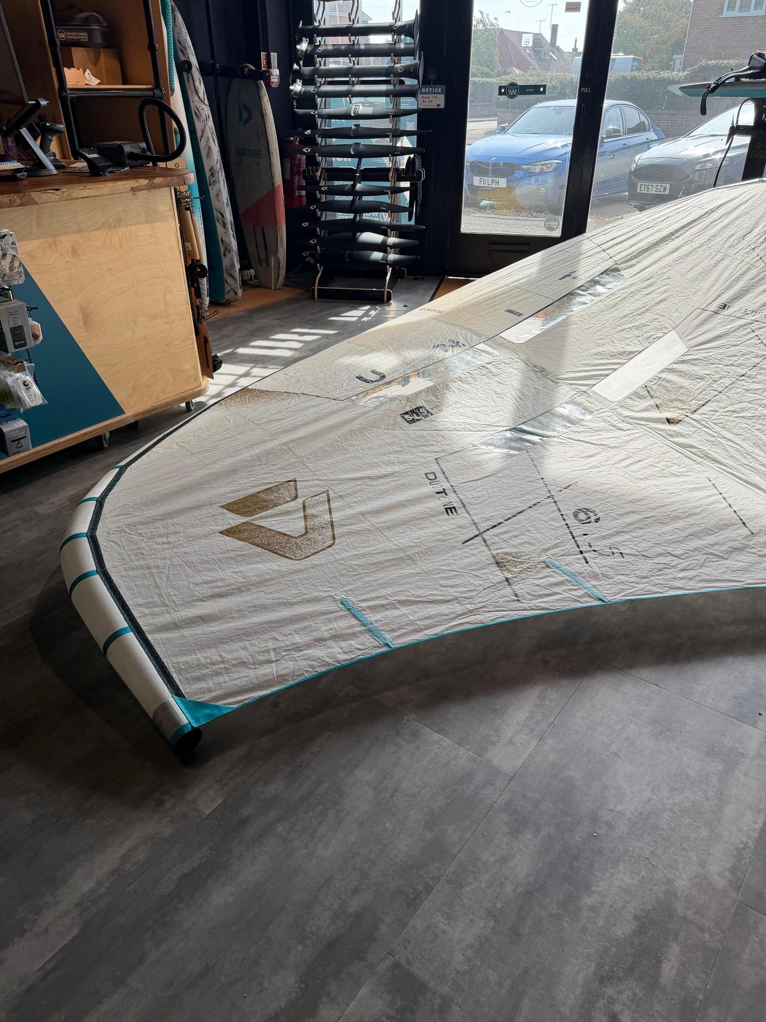 Used 6.5m Duotone Unit SLS Concept Blue wing in off-white with teal accents and fusion boom, displayed in a shop.