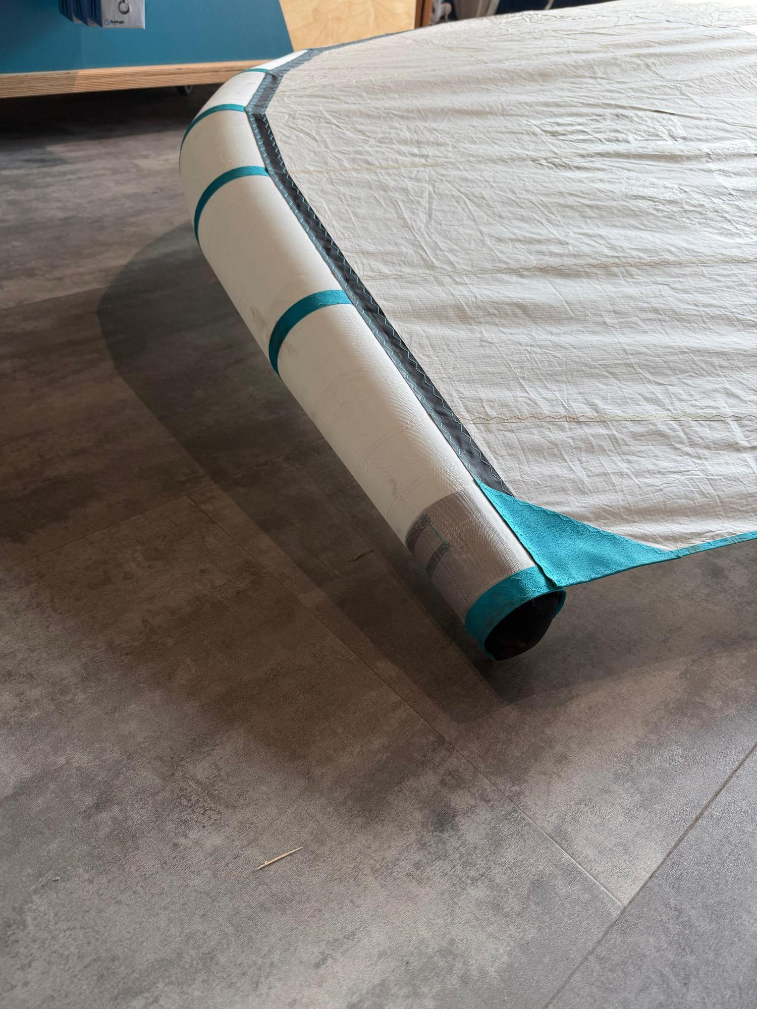 Used Duotone Unit SLS 6.5M Concept Blue wing with white leading edge and turquoise detailing on a grey floor.