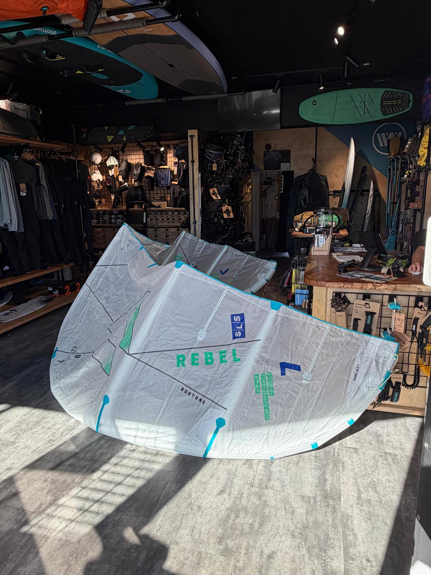 Used 7m Duotone Rebel SLS Concept Blue kite in white with teal accents, displayed on a shop floor.