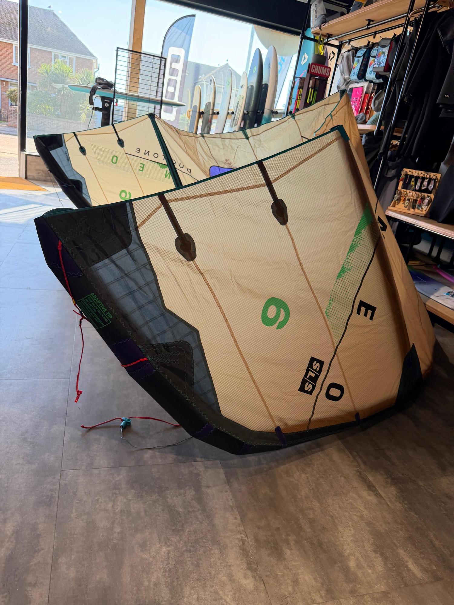 Used Duotone Neo SLS 6m wave kite in beige and black with green detailing, displayed on a shop floor.