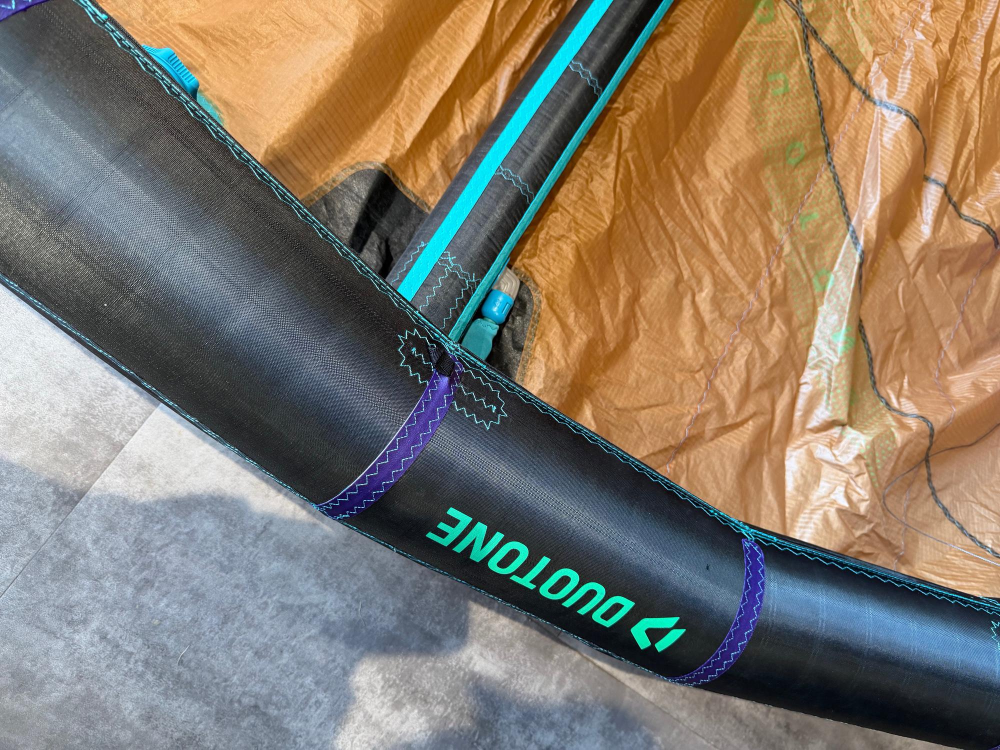 Close-up of a 6m Duotone Neo SLS wave kite featuring a black leading edge, teal branding, and brown canopy material.