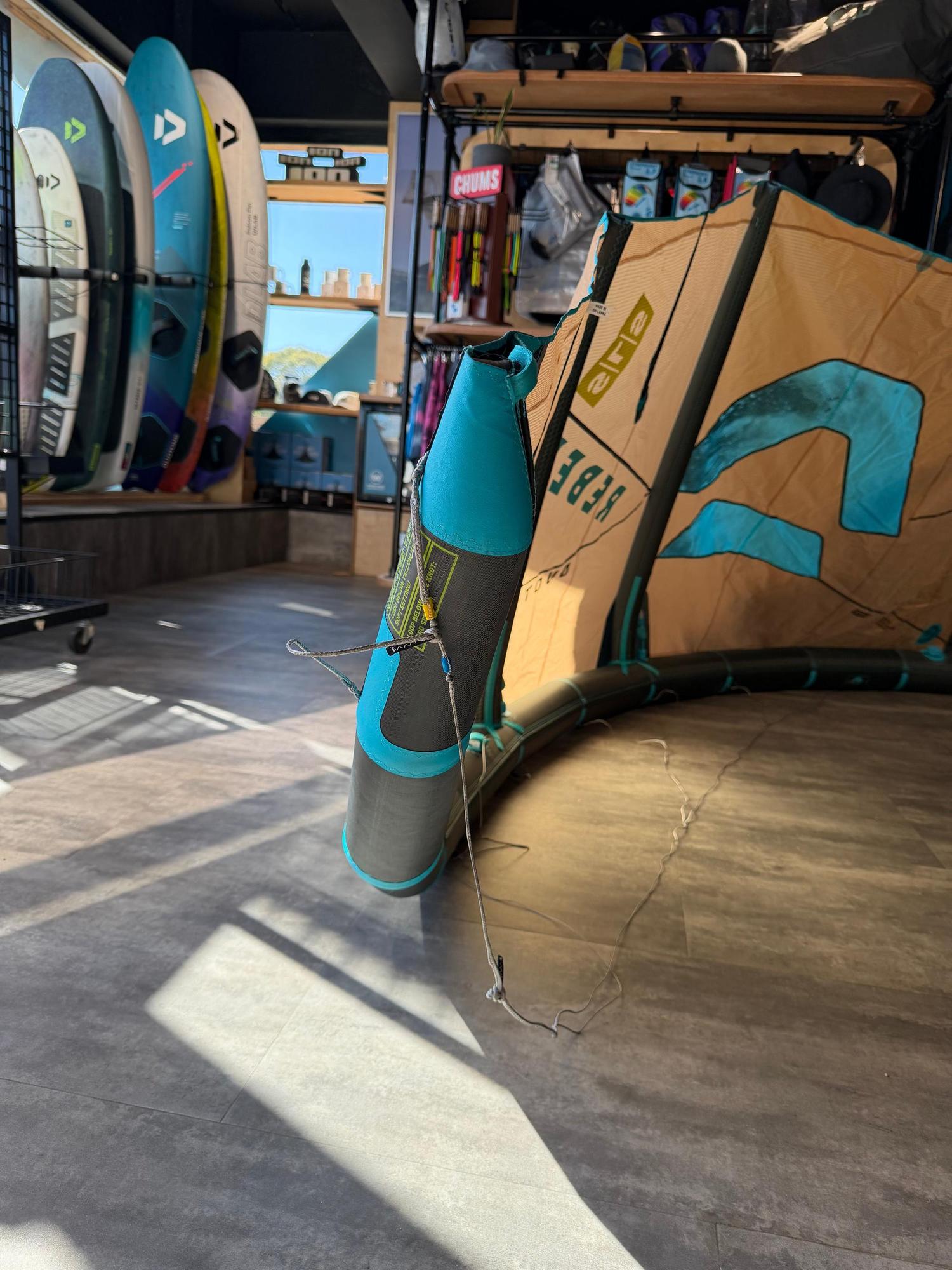 Used 8m Duotone Rebel SLS 2026 big air kite in tan and teal, featuring durable Penta TX material in a shop setting.