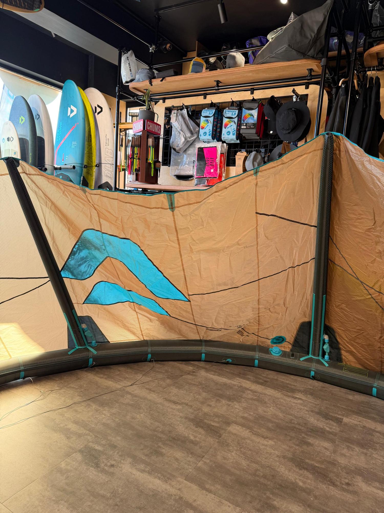 Used 8m Duotone Rebel SLS 2026 kite in tan and teal with Penta TX material, displayed in a retail shop.