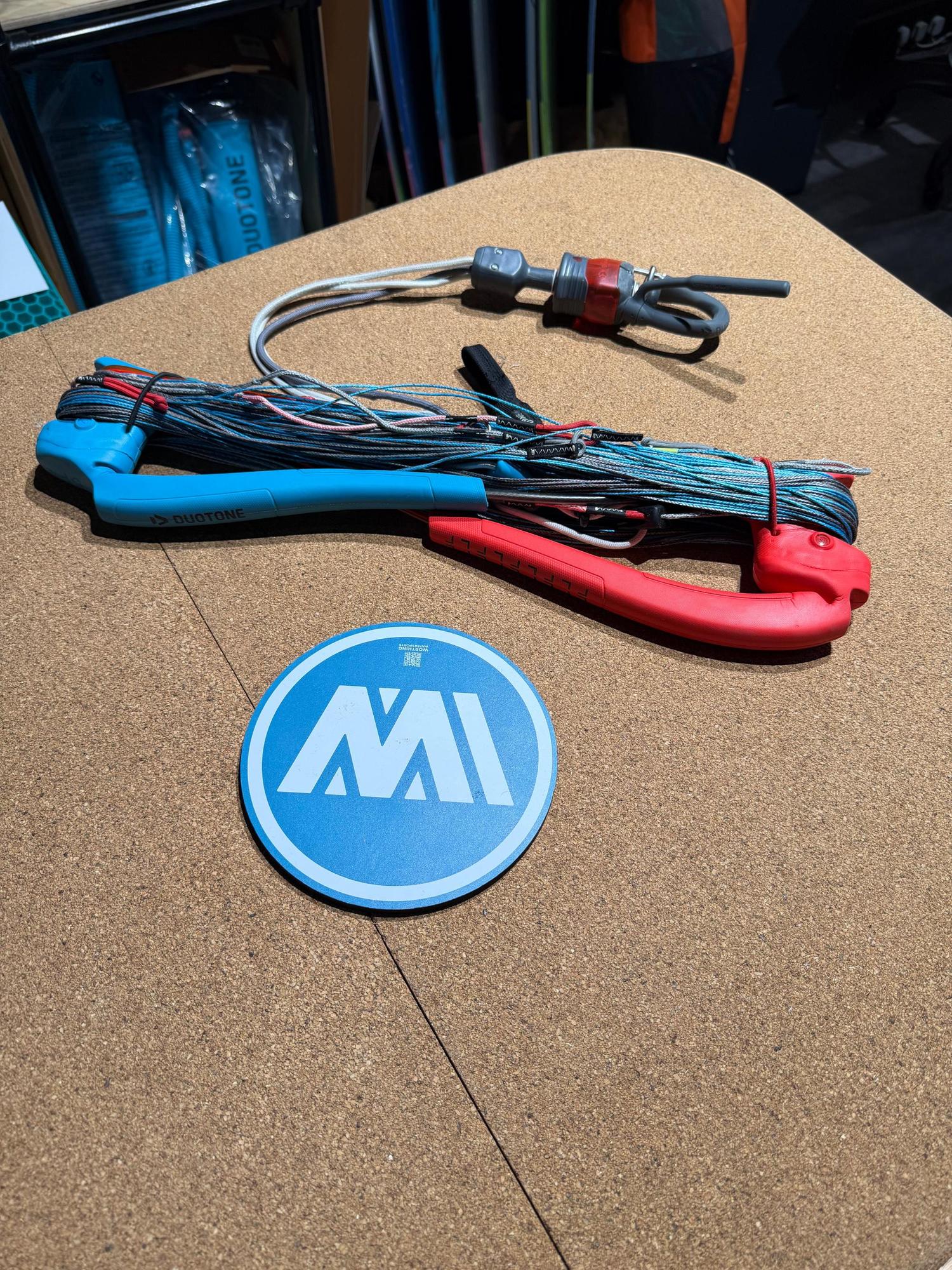 Used Duotone Trust Bar S-M with blue and red grips, wound kite lines, and a Click-In safety system on a cork surface.