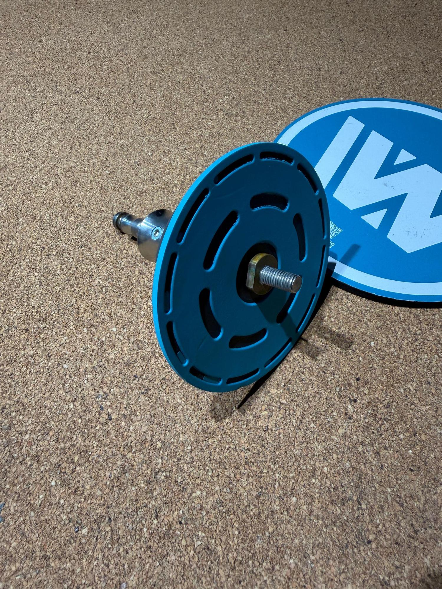 Used Duotone iBase 2.0 windsurfing mast base with blue circular plate and metal connector on a cork surface.