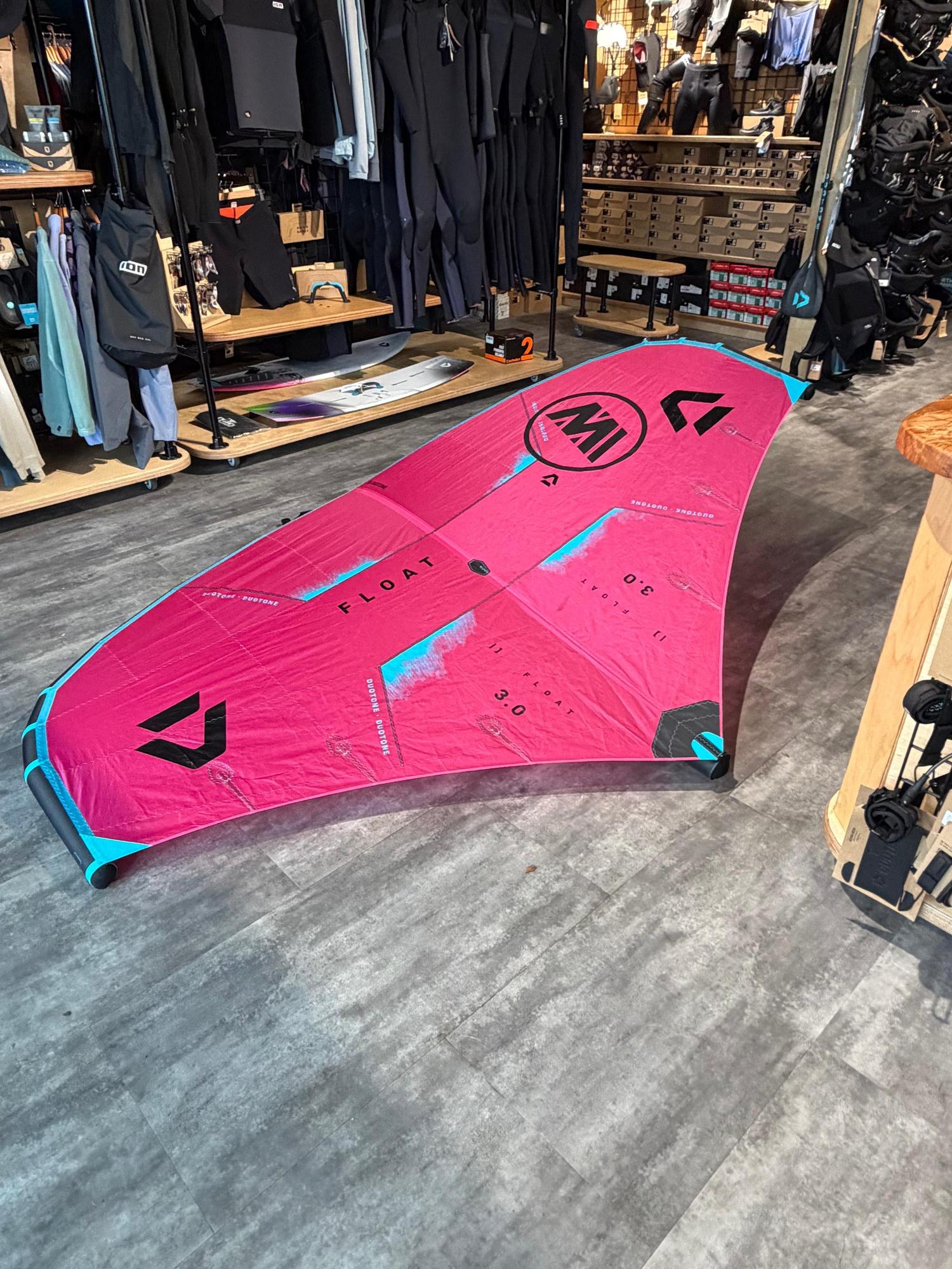 Used 3m Duotone Float wave wing in pink and blue, featuring a boom and black branding, displayed on a shop floor.