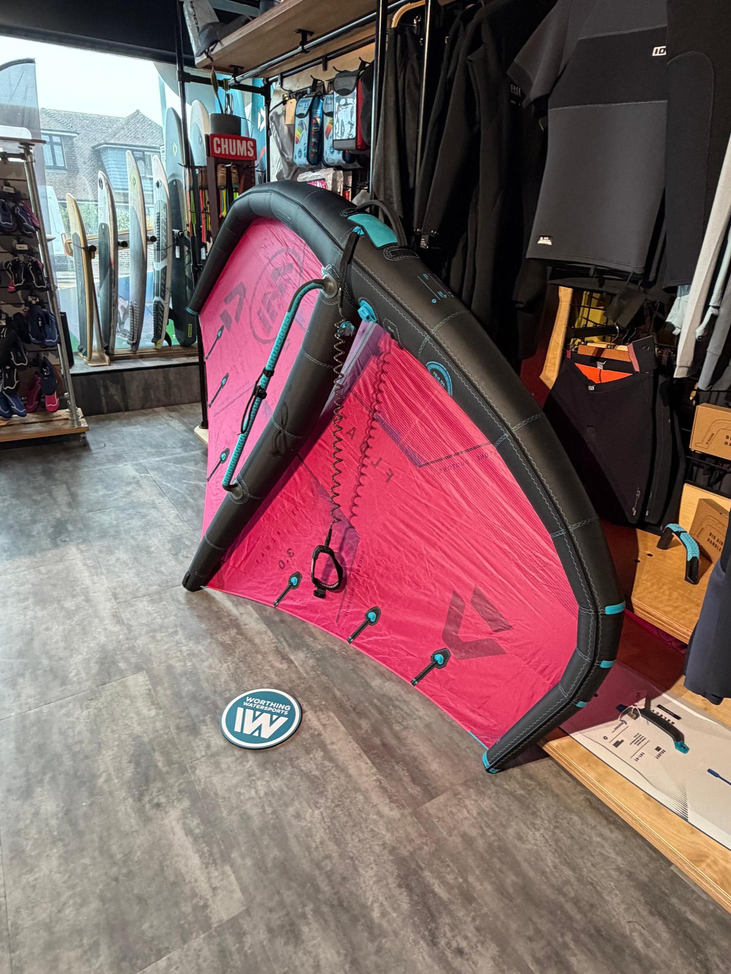Used Duotone Float 3m wave wing in pink and black with an integrated boom, displayed in a watersports shop.