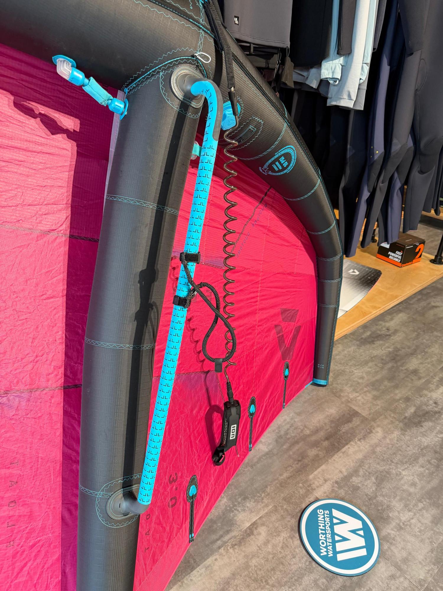 Used Duotone Float 3m wave wing in pink and black with a blue boom, displayed in a shop.