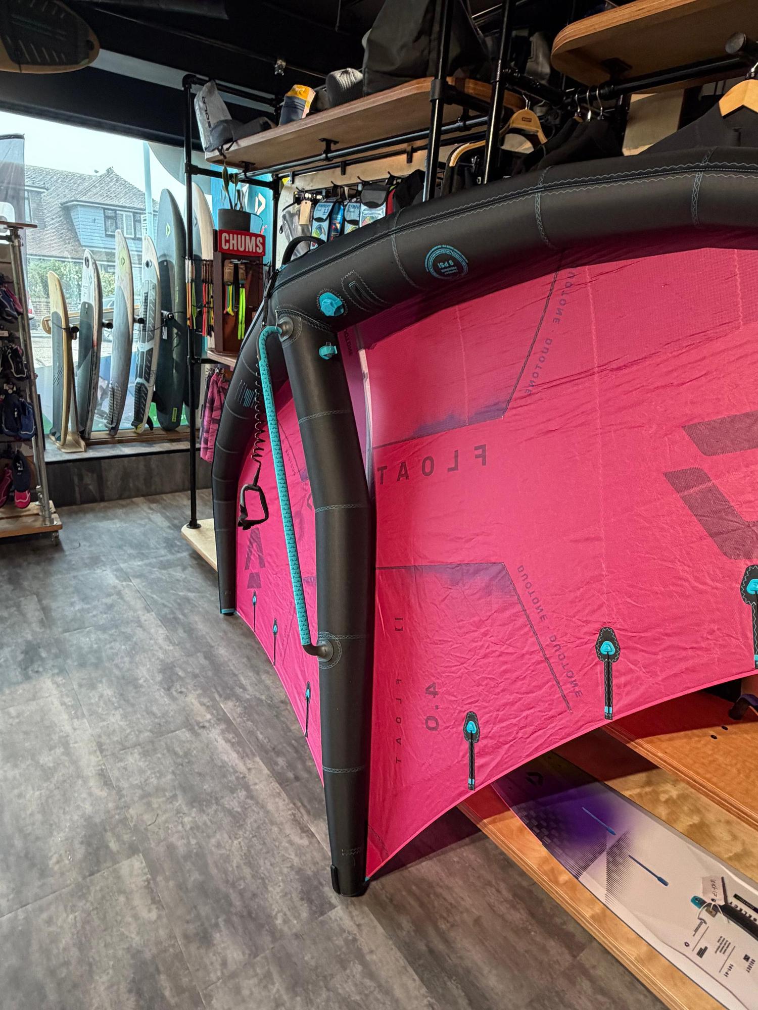 Used Duotone Float 4m wave wing in pink and black with boom and leash, displayed in a retail shop.