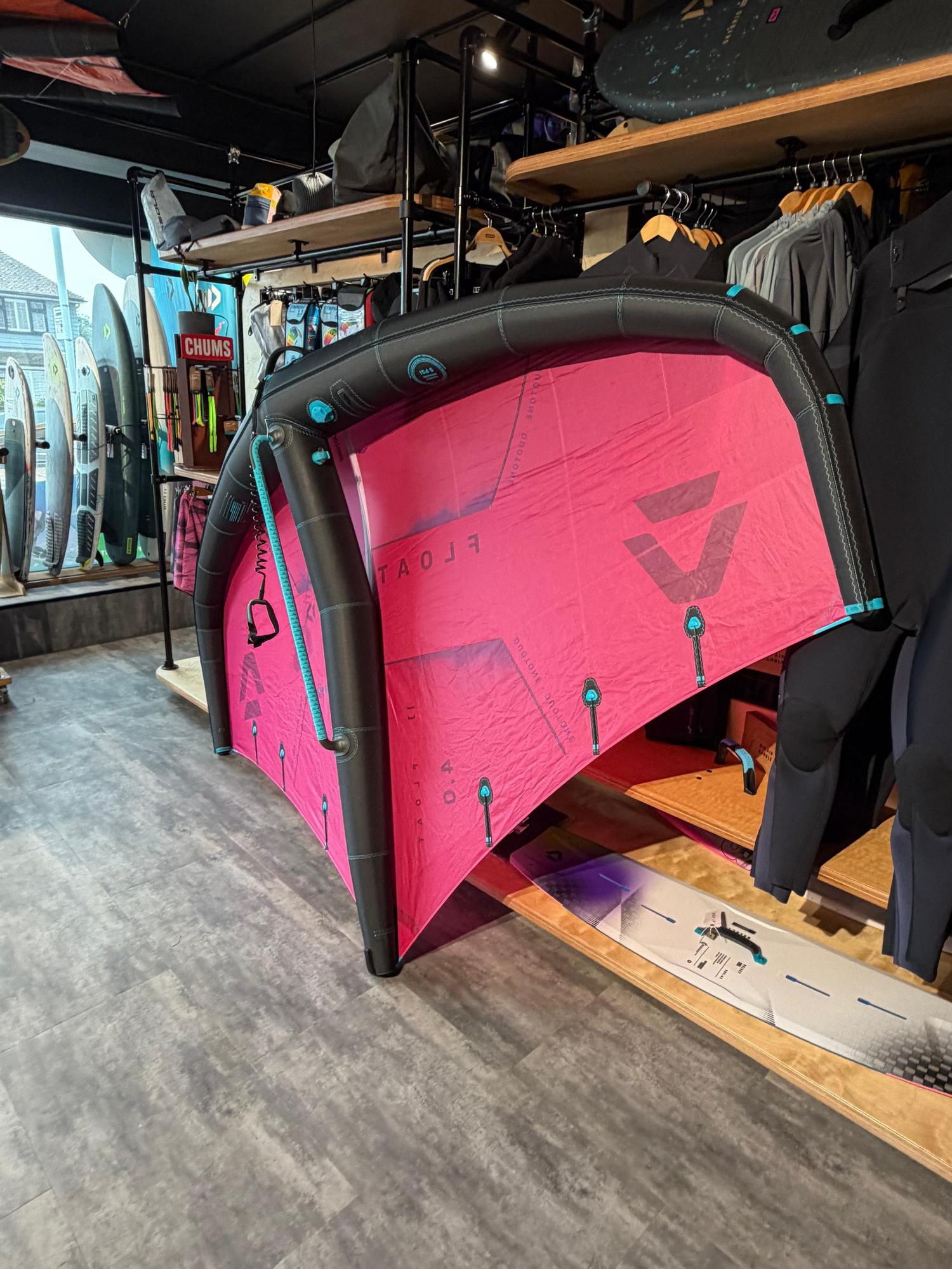 Used Duotone Float 4m wave wing in pink and black, featuring a rigid boom design and leash, displayed in a retail shop.