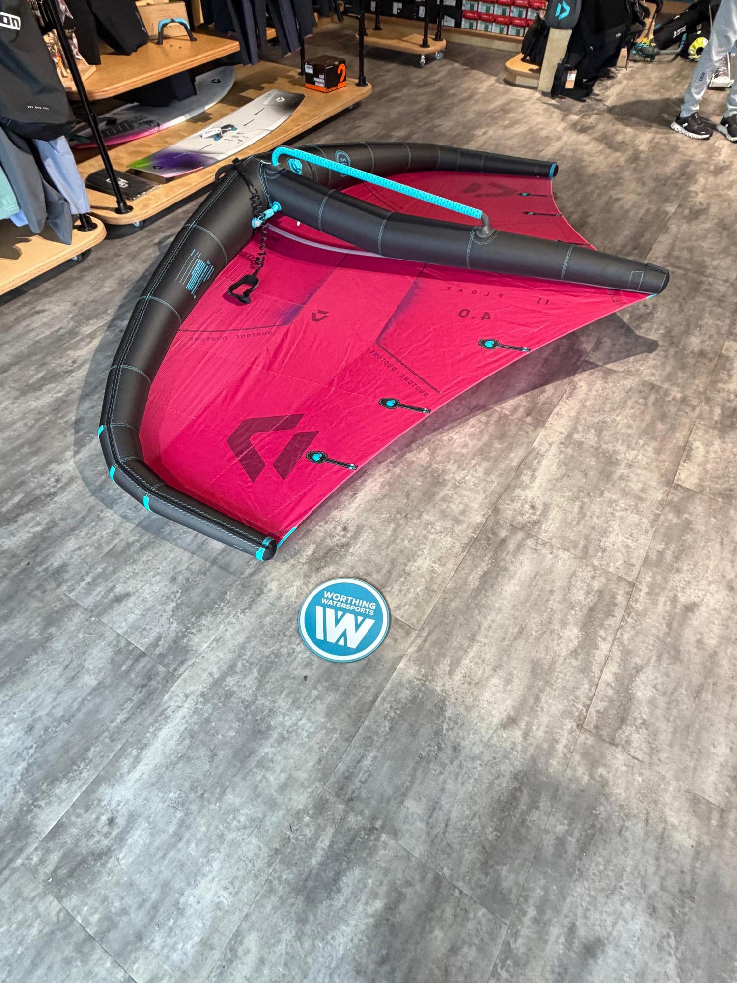 Used 4m Duotone Float wave wing in red and black with a blue boom and leash, displayed on a grey shop floor.