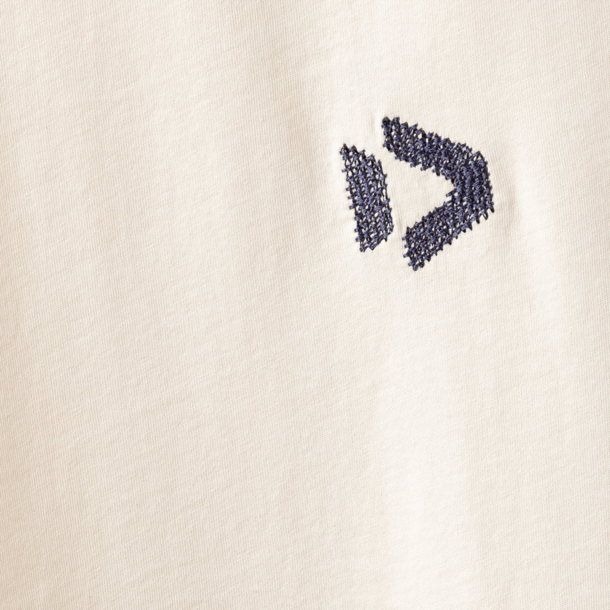 Close-up of an undyed men's Duotone tank vest top featuring a dark blue embroidered logo on light cream fabric.